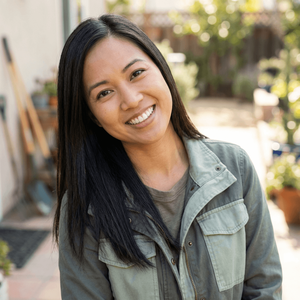 Woman in her 40s smiling in her backyard near a house